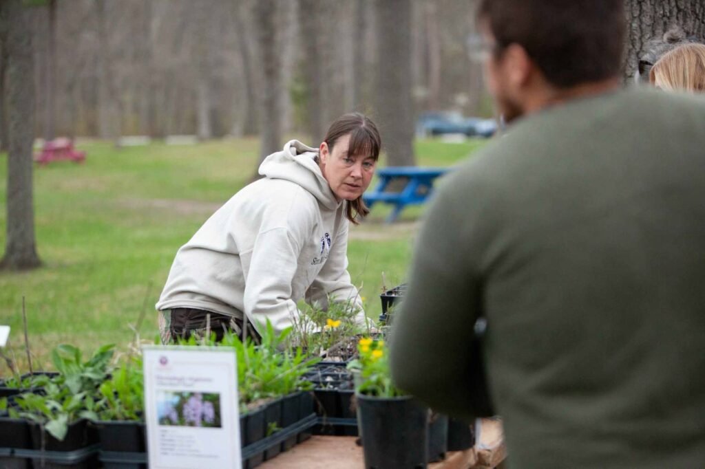 A grower from Thedford Native Plants at her table of seedlings